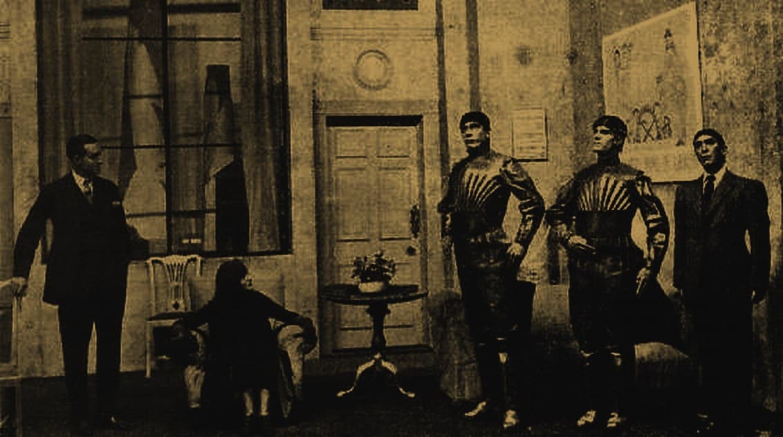 Scene from Karel Čapek's play R.U.R. (1921): two actors in robot costumes on stage beside human characters.